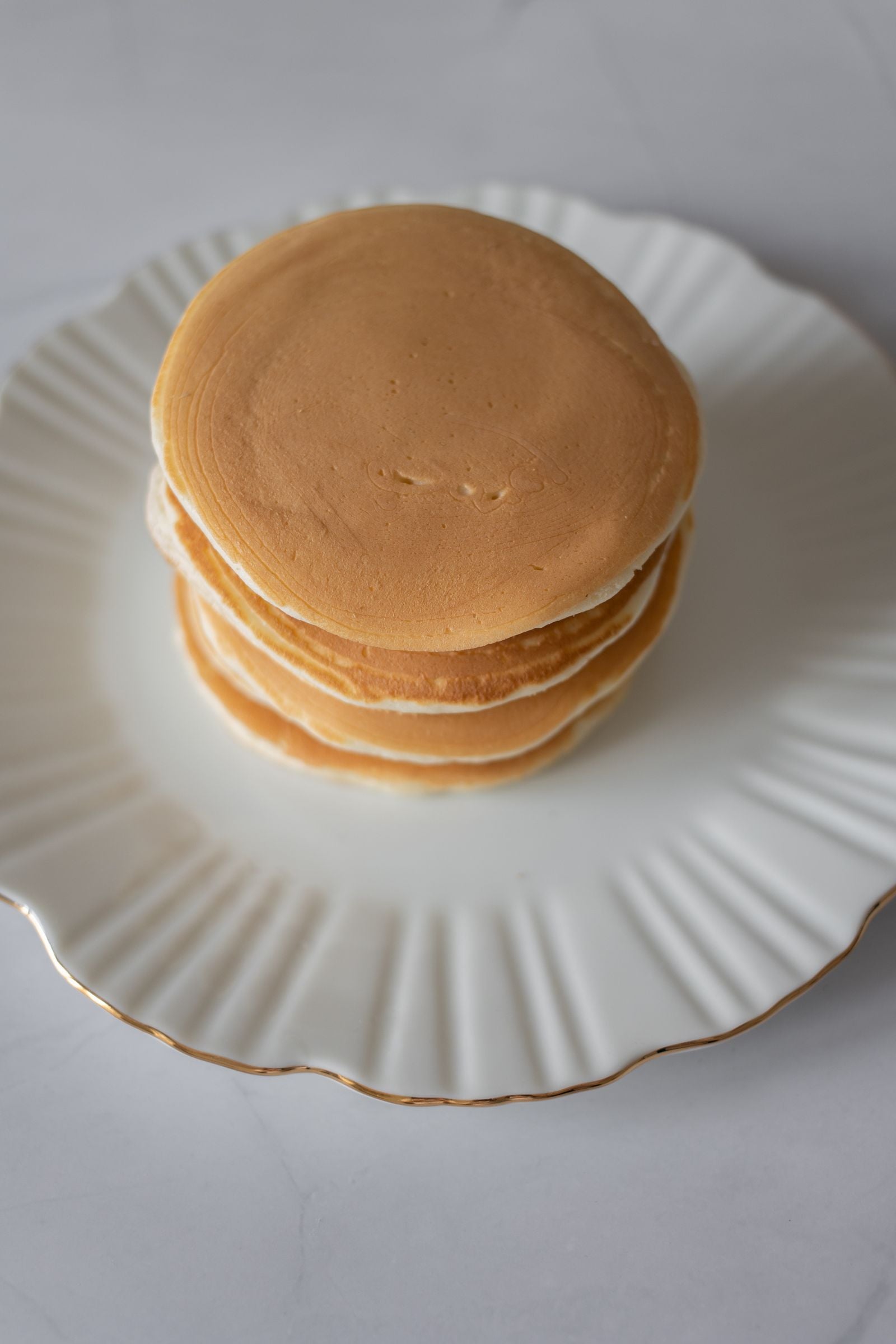 A short stack of fluffy keto pancakes on a white plate